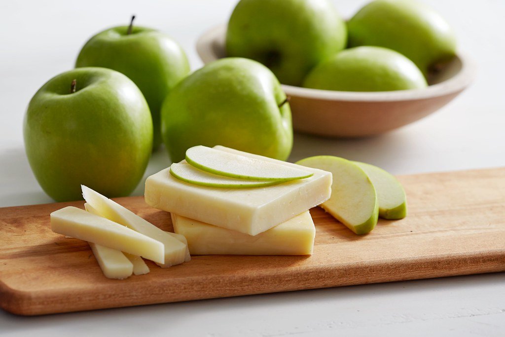 Wooden chopping board with apples and cheese